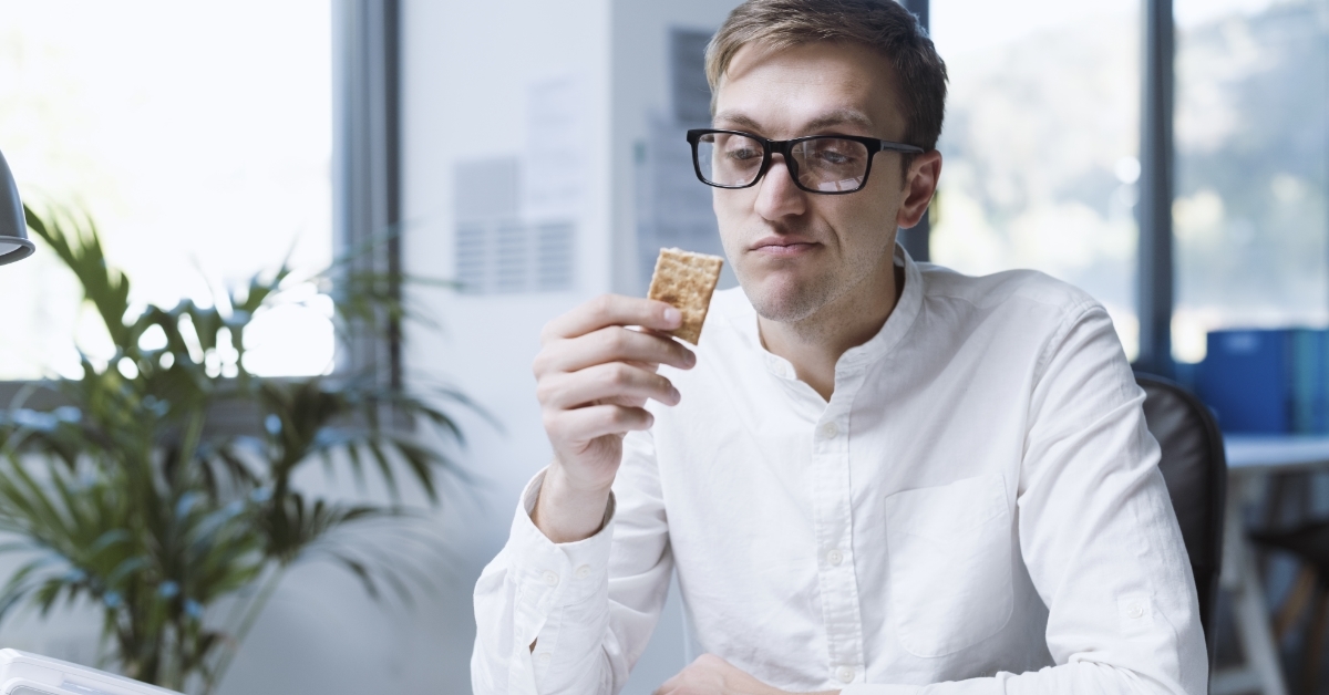 depressed male employee eating biscuit