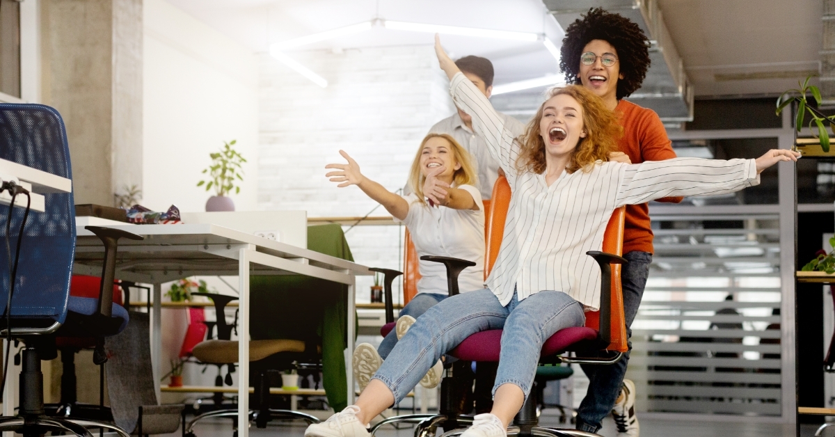 female employees playing with office chairs