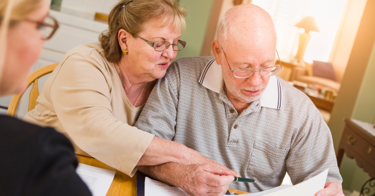 senior couple signing documents with agent