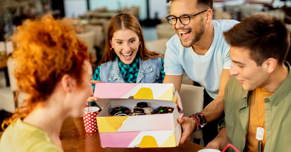 man surprising friends with donuts box
