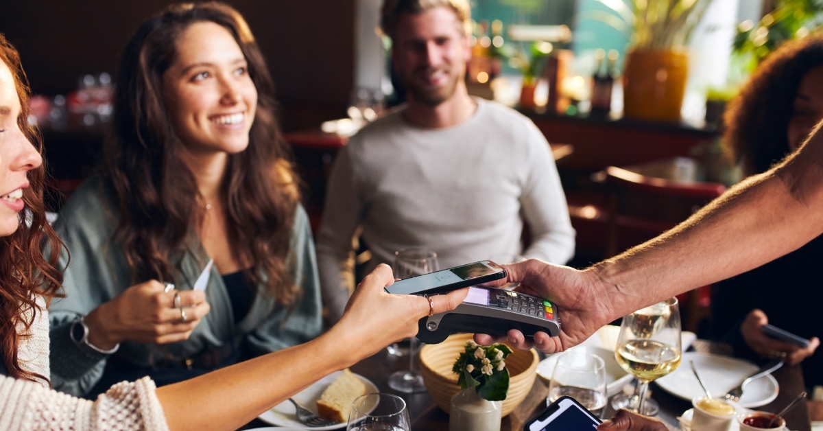 friends paying contactlessly in restaurant