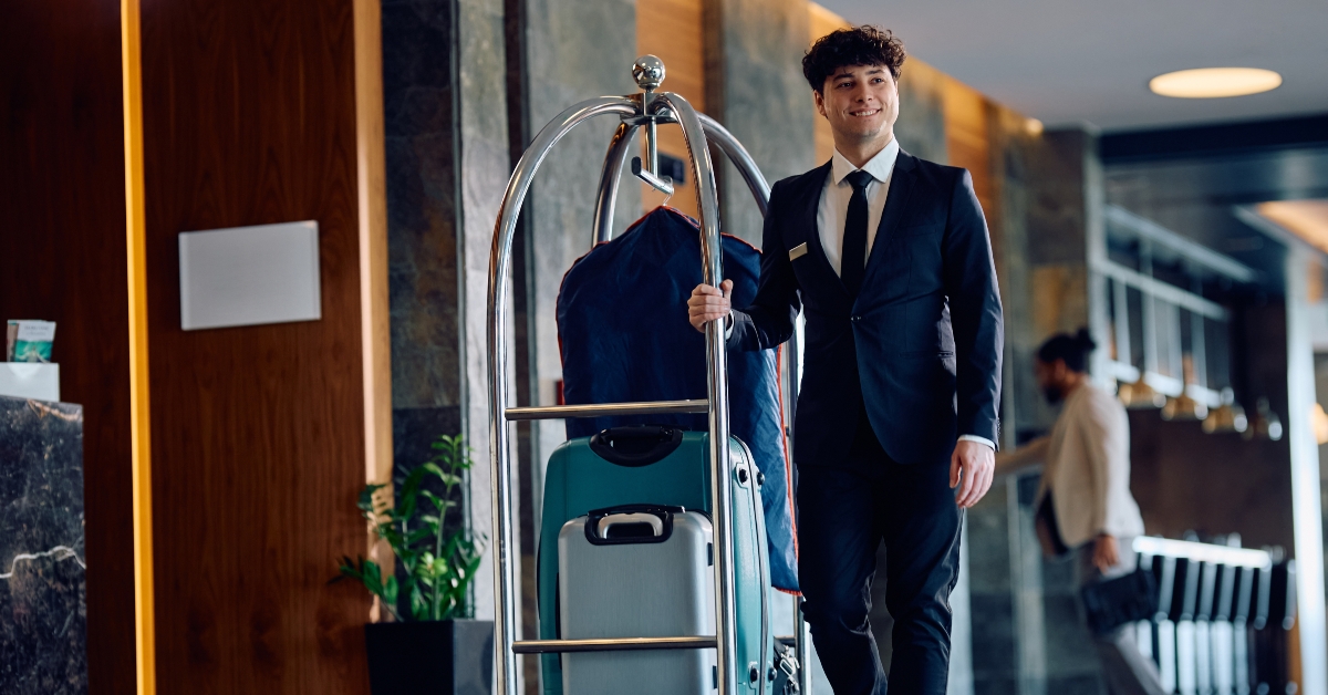 happy bellboy pushing luggage cart