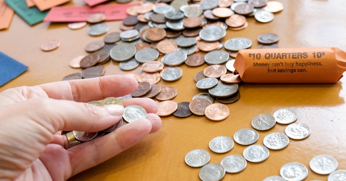 man counting pennies at wooden table