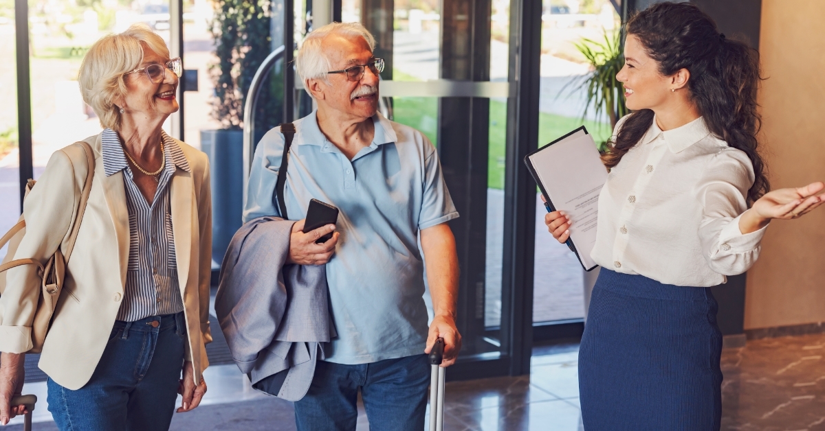 cheerful hotel receptionist greeting senior couple
