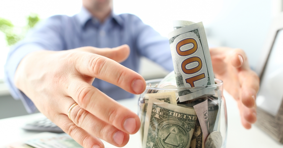 man grabbing savings jar greed concept