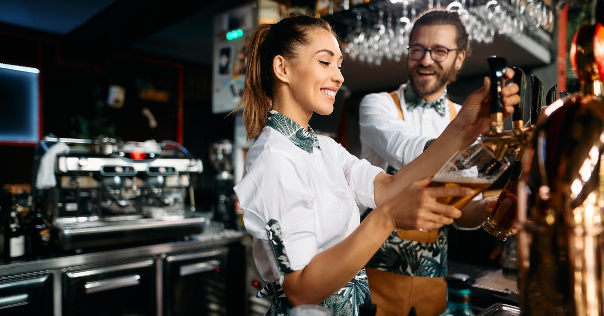 Female bartender pours beer