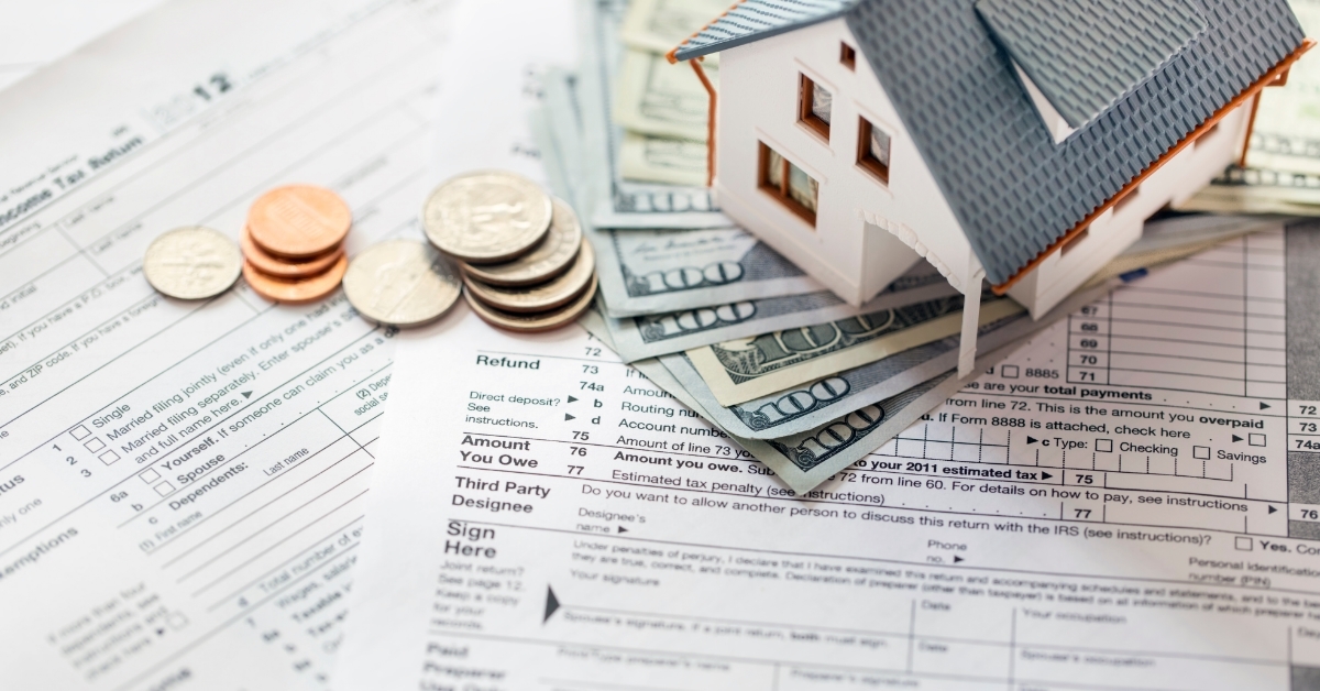 miniature house with money on tax papers