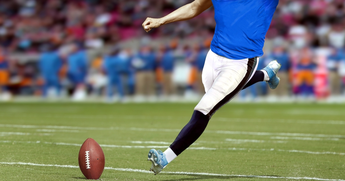 American football player kicking ball