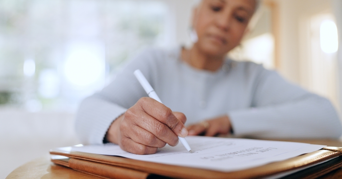 senior woman signing insurance policy at home