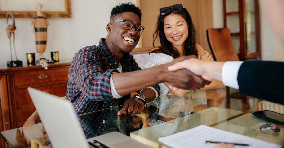 Couple handshaking realtor after signing contract