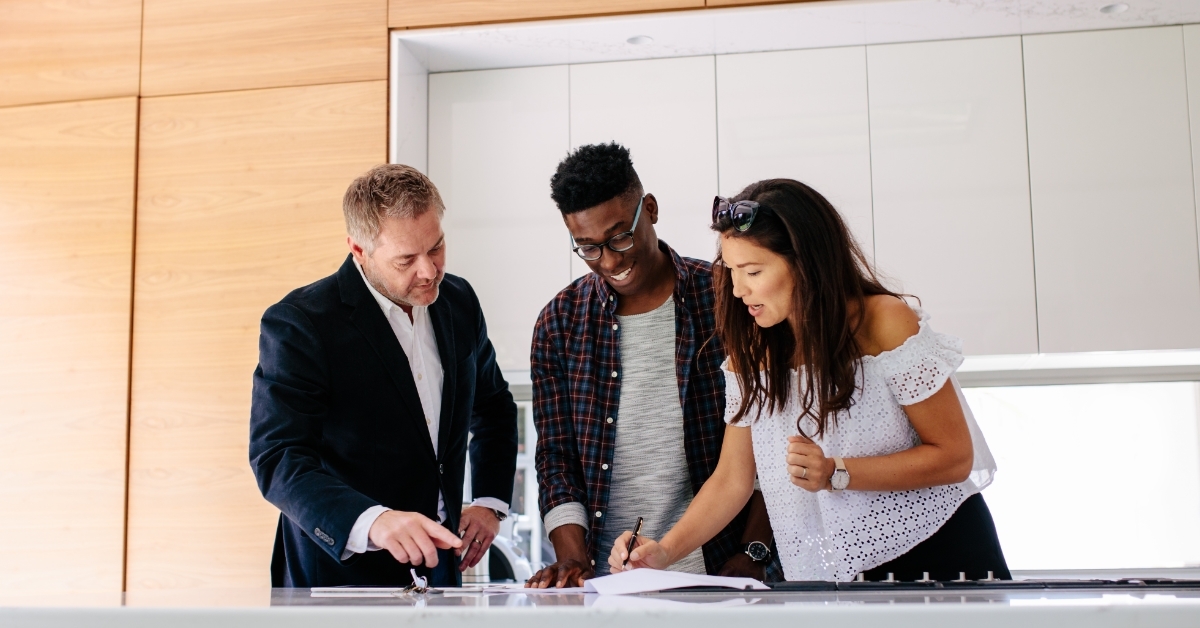 multi ethnic couple signing mortgage contract with realtor