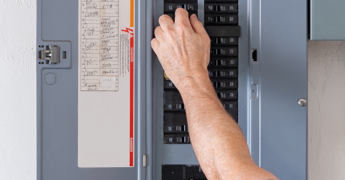 man Resetting tripped breaker in power panel