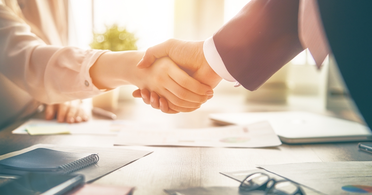 Shaking hands above desk
