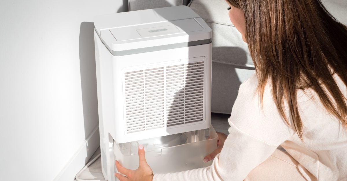 Woman changing water in dehumidifier