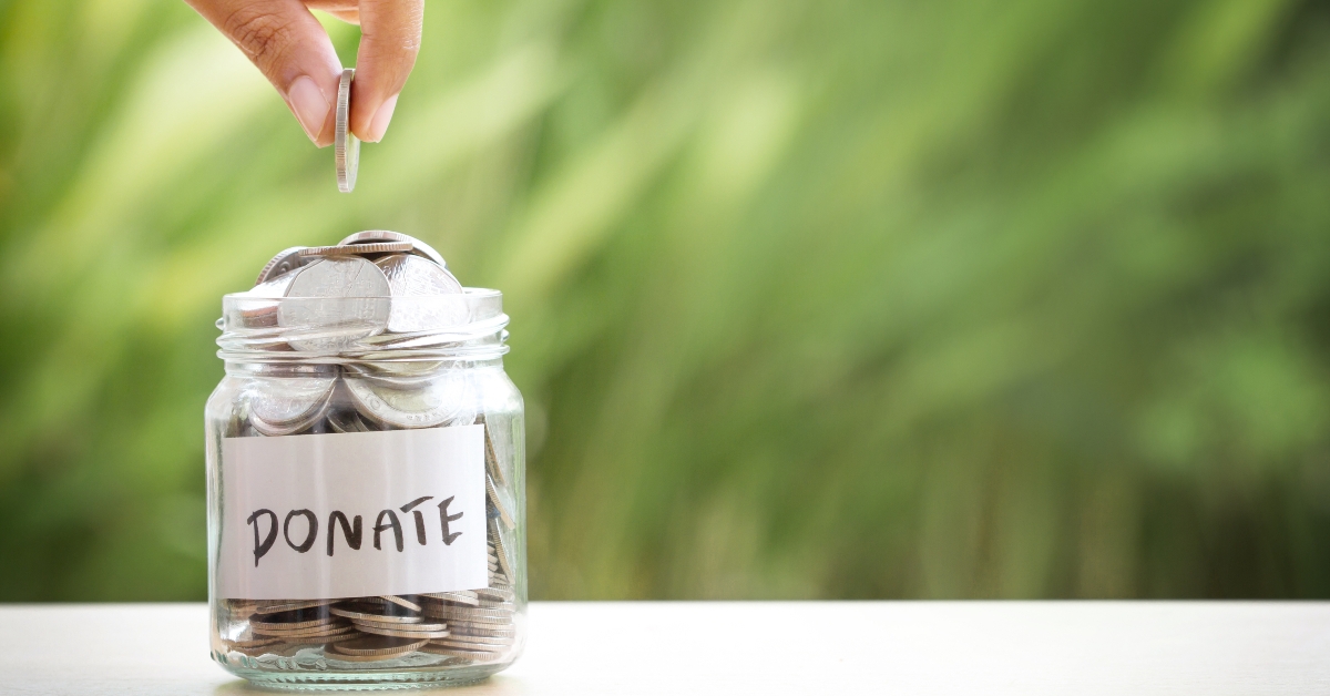 hand putting coins in glass jar