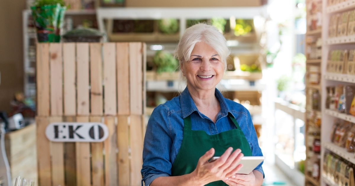 senior female store assistant posing with tablet