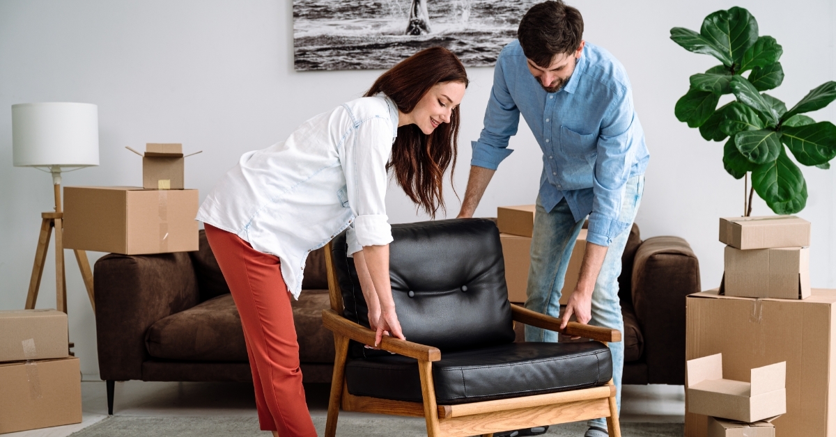 happy couple arranging furniture in new home