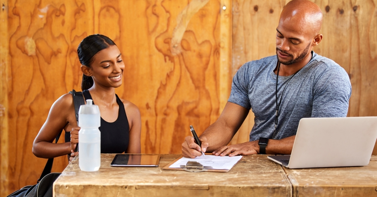 Personal trainer signing membership for female client