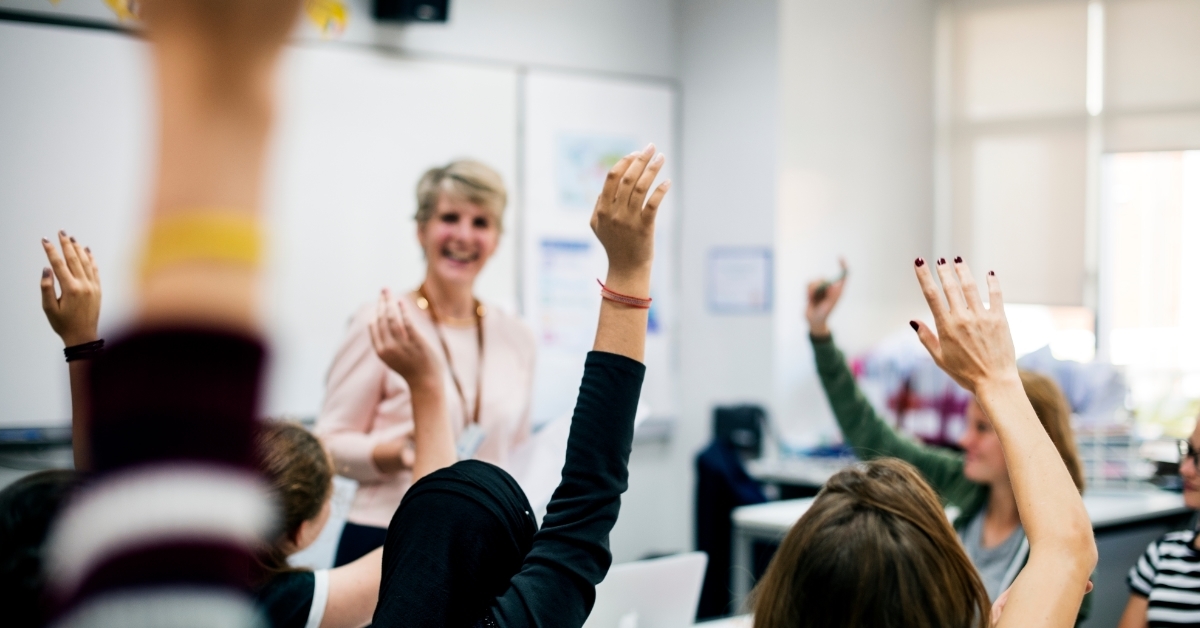 students raising hands in classroom