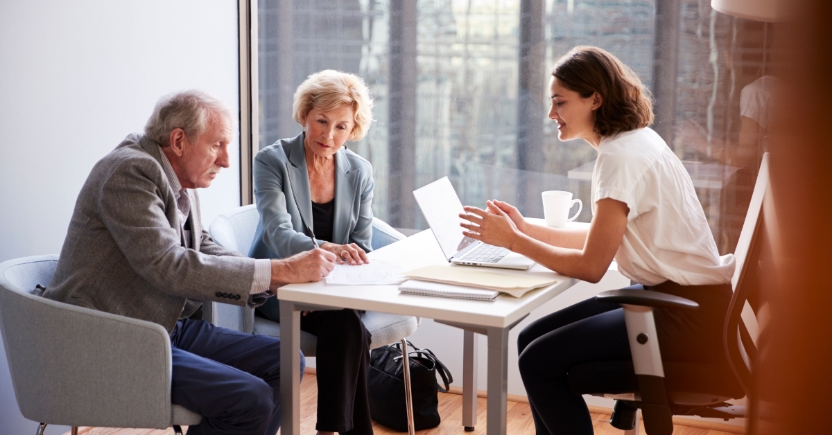 senior couple signing documents with finance advisor