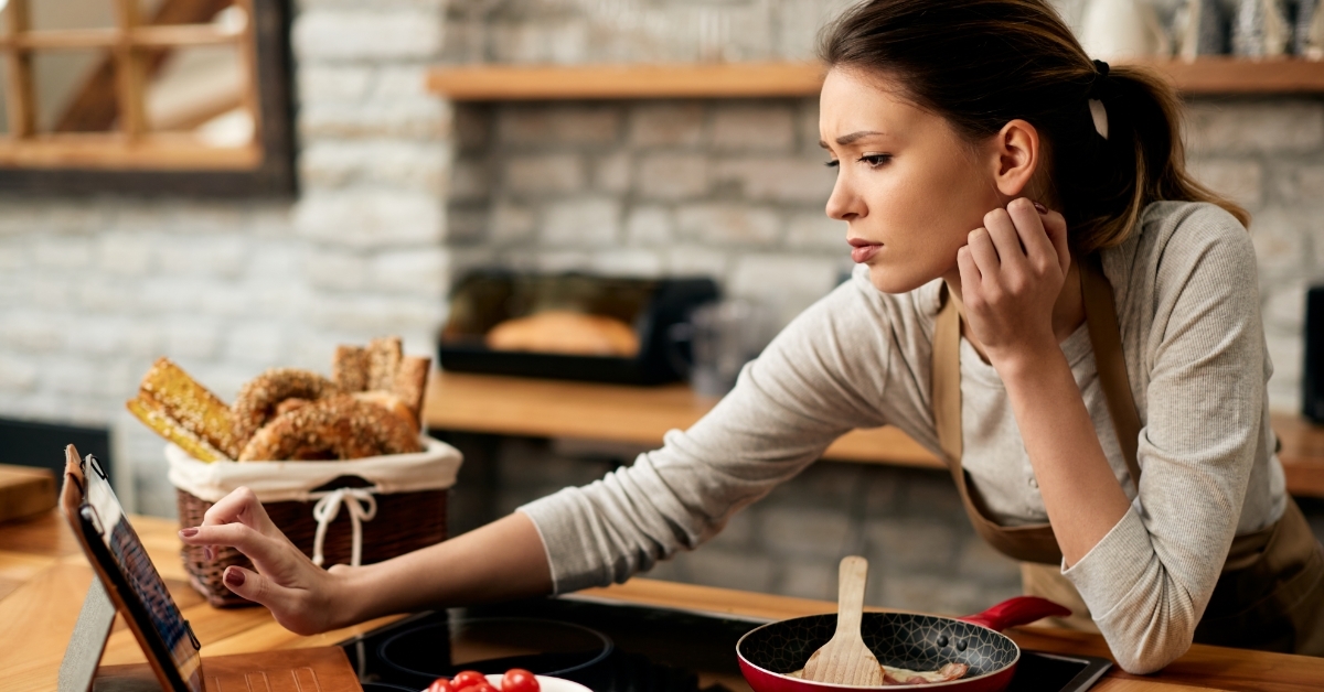 woman cooking while reading recipe on tablet