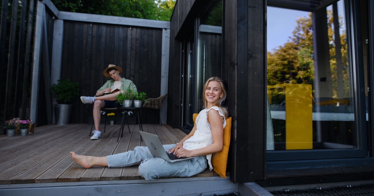 couple with laptop resting outside tiny house