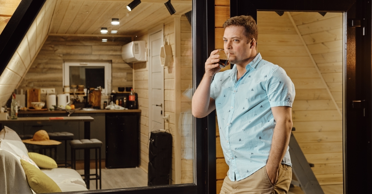 man drinking juice on log cabin terrace