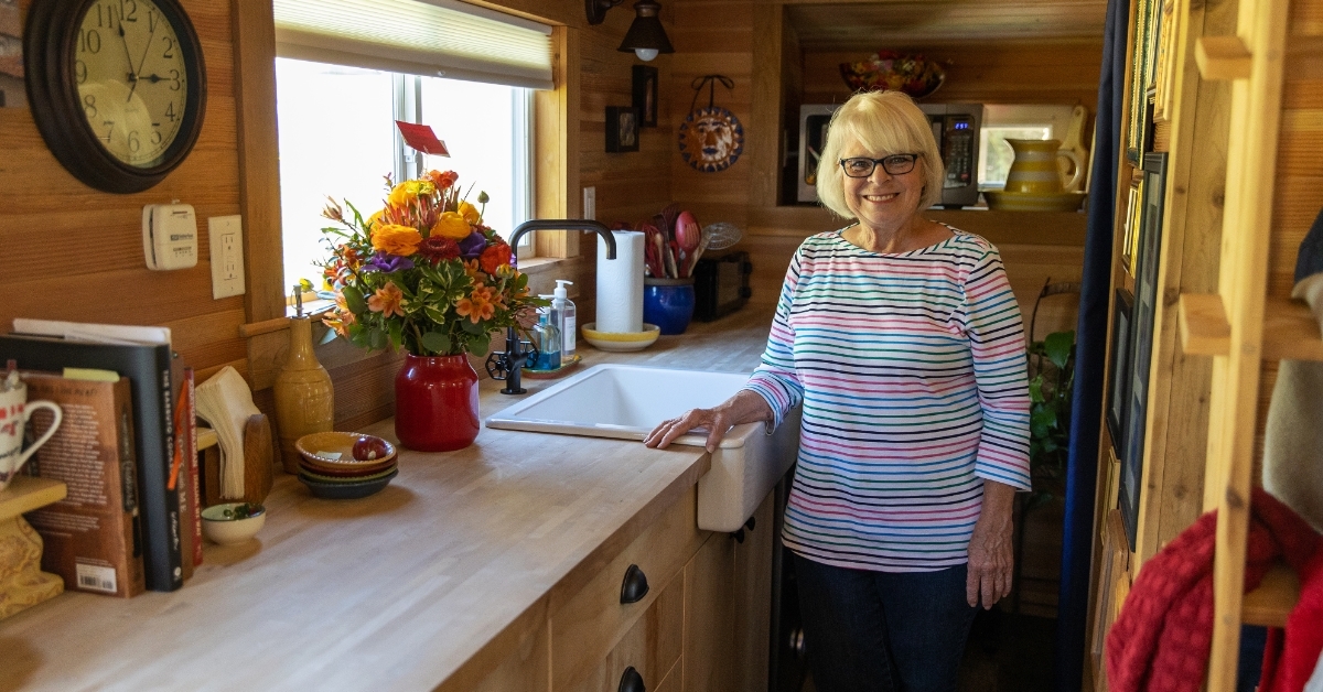 senior woman standing besides sink 