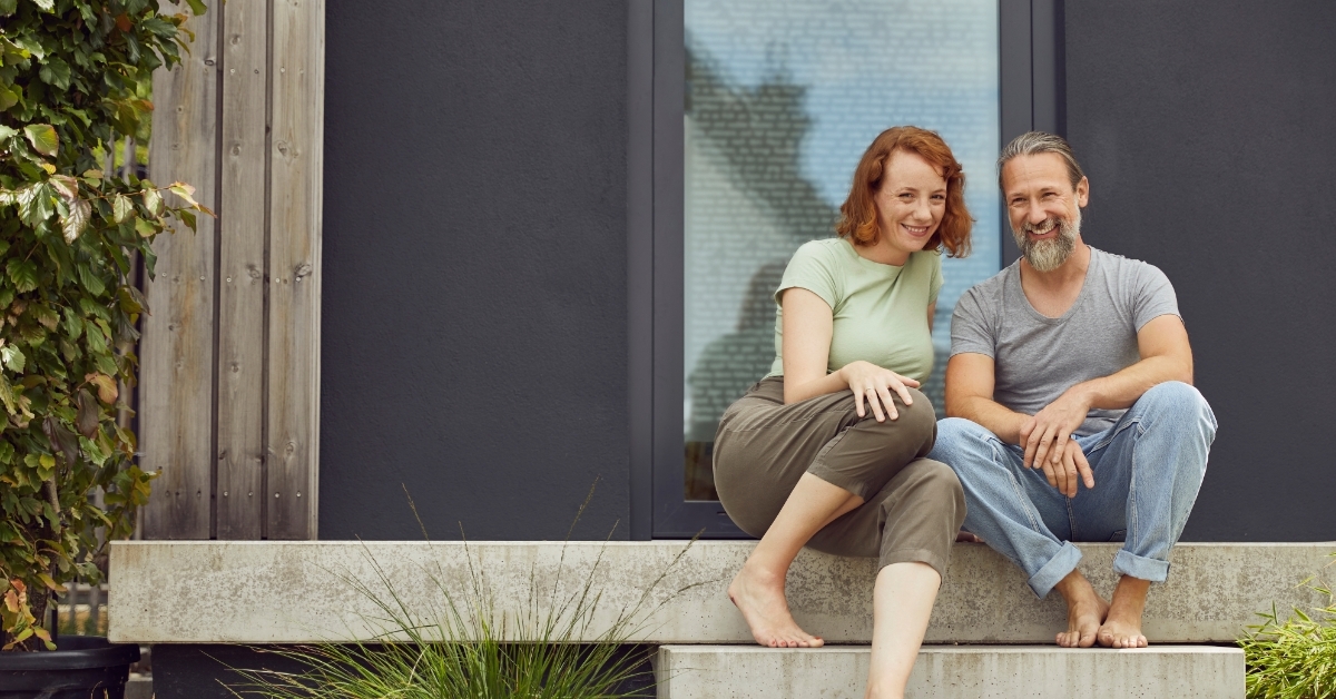 Smiling couple sitting on tiny house steps
