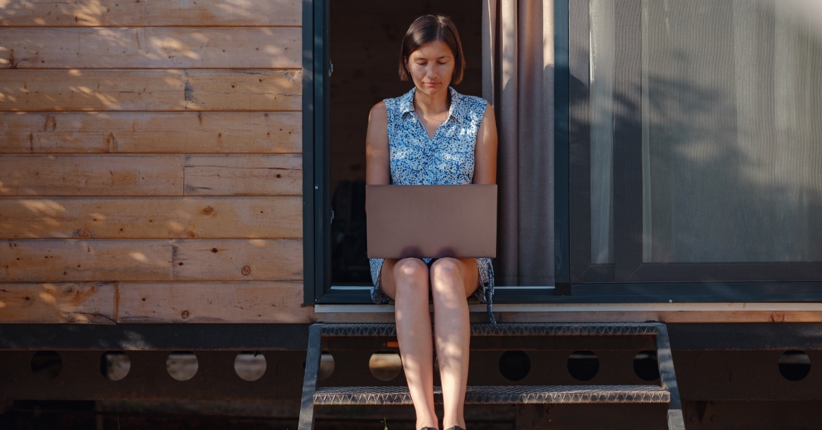 woman with laptop resting outside vacation home