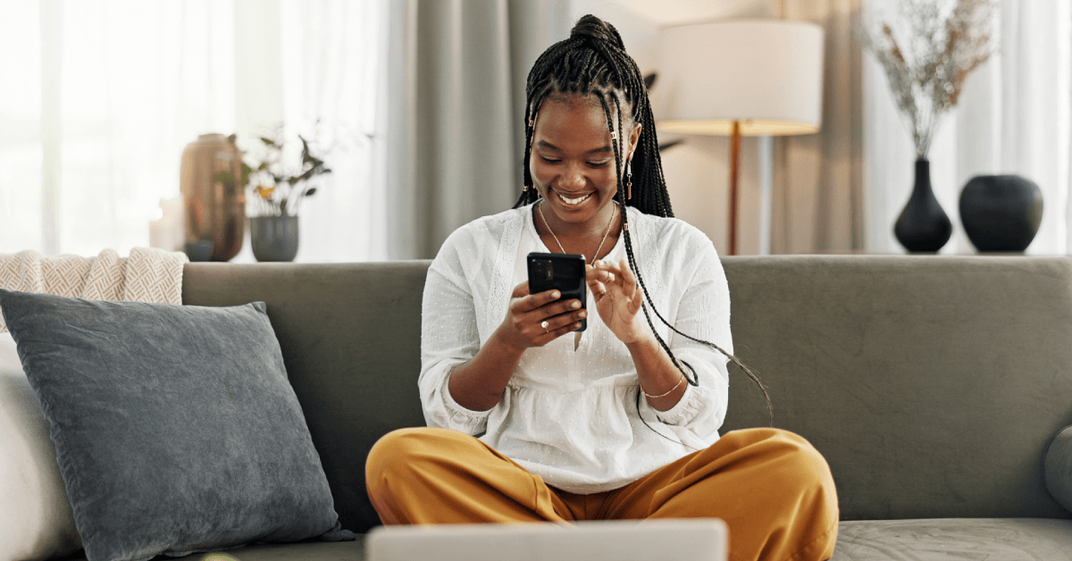 A woman uses her phone while sitting on the couch.