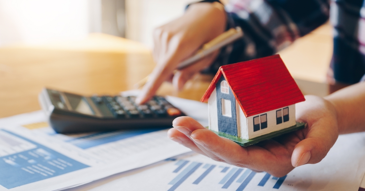 woman holding house model calculating mortgage amount