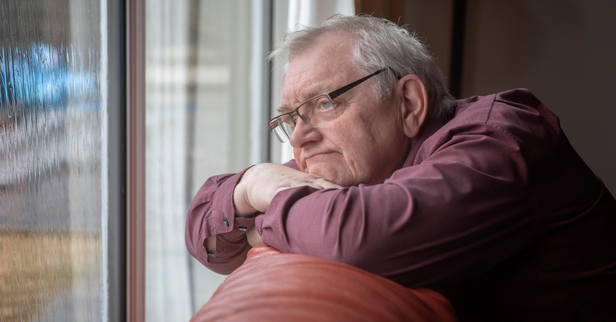 depressed senior man looking out of window