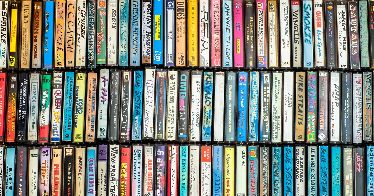 impressive and neat collection of old casset tapes on a shelf stacked vertically