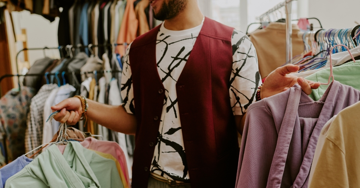 Smiling man browsing clothes in thrift store