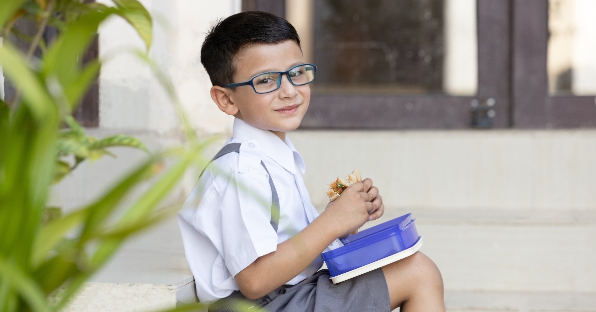 Boy eating sandwich out of his lunch box