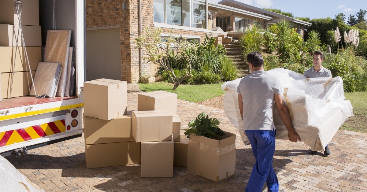 movers carrying sofa from van to house