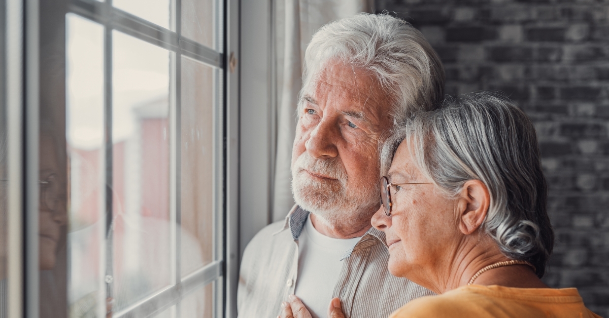 Depressed senior couple looking out of window