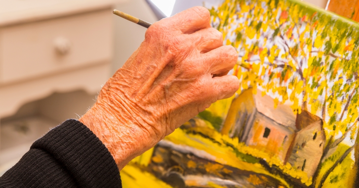 Senior woman painting canvas at home