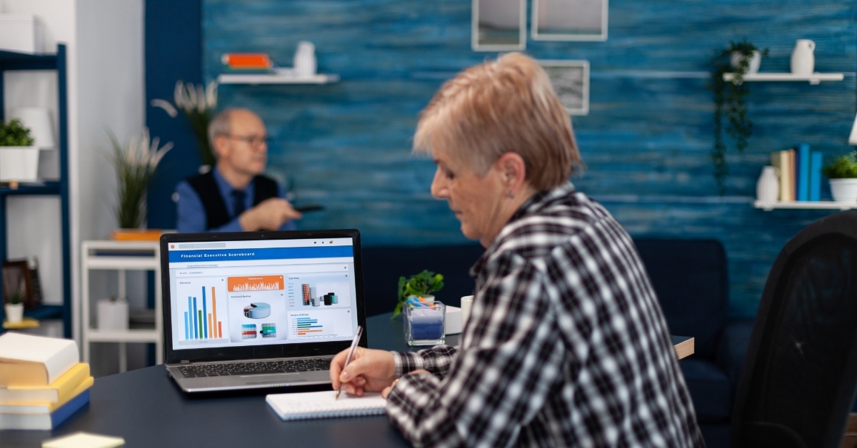 senior woman making notes using laptop