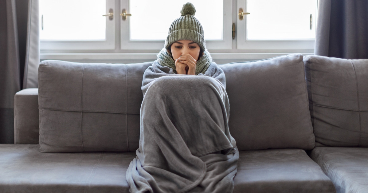 woman freezing on the couch trying to keep warm