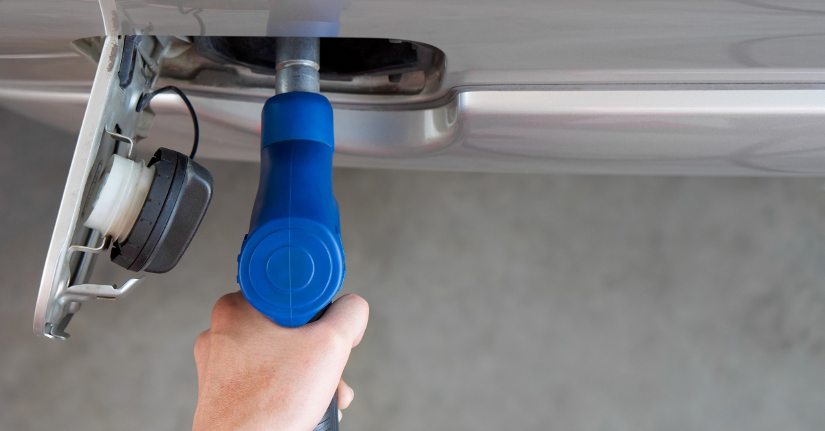 Hand holding blue gas pump nozzle