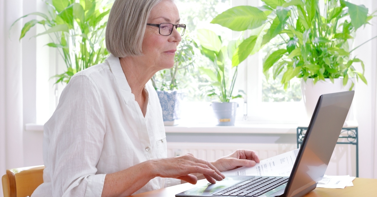 senior woman with receipts infront of laptop