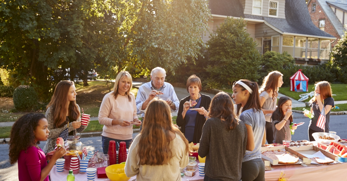 Neighbours talk and eat around a table at a block party 