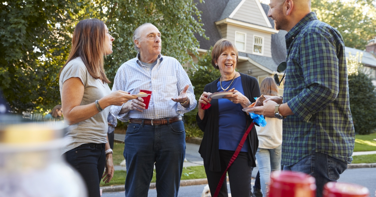 Middle aged and senior neighbours talking at a block party 
