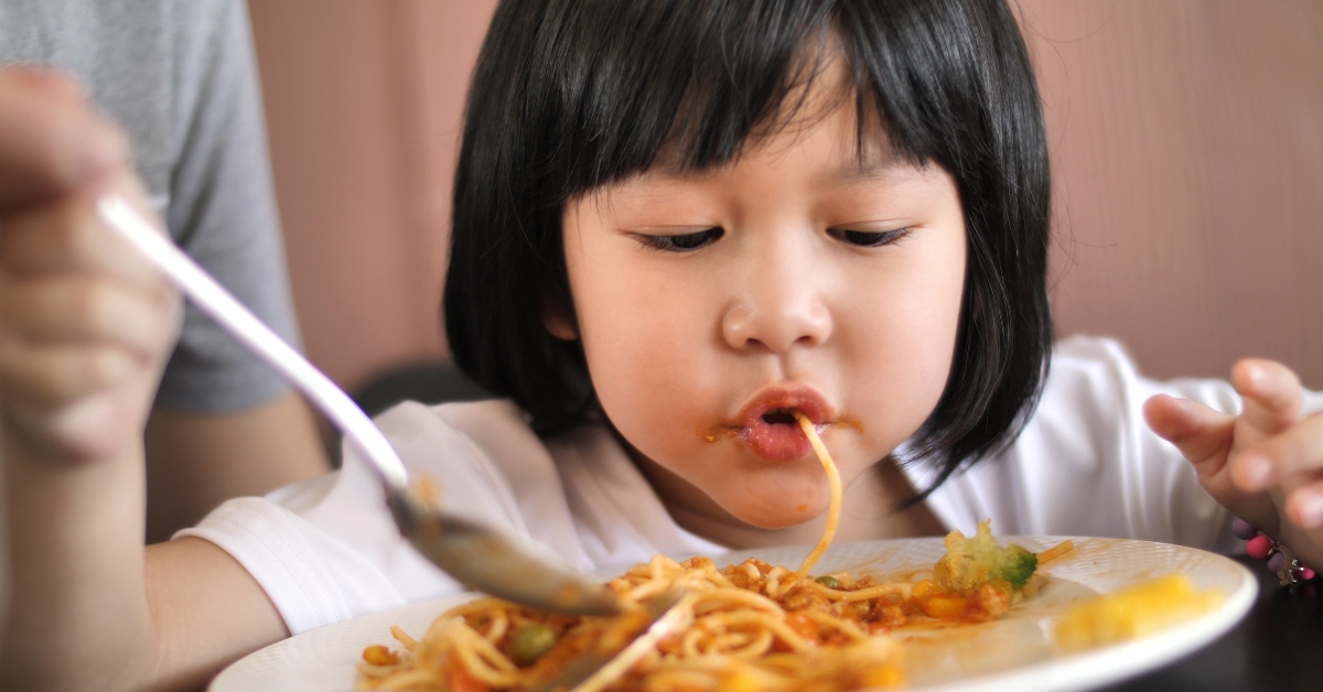 child eating delicious spaghetti