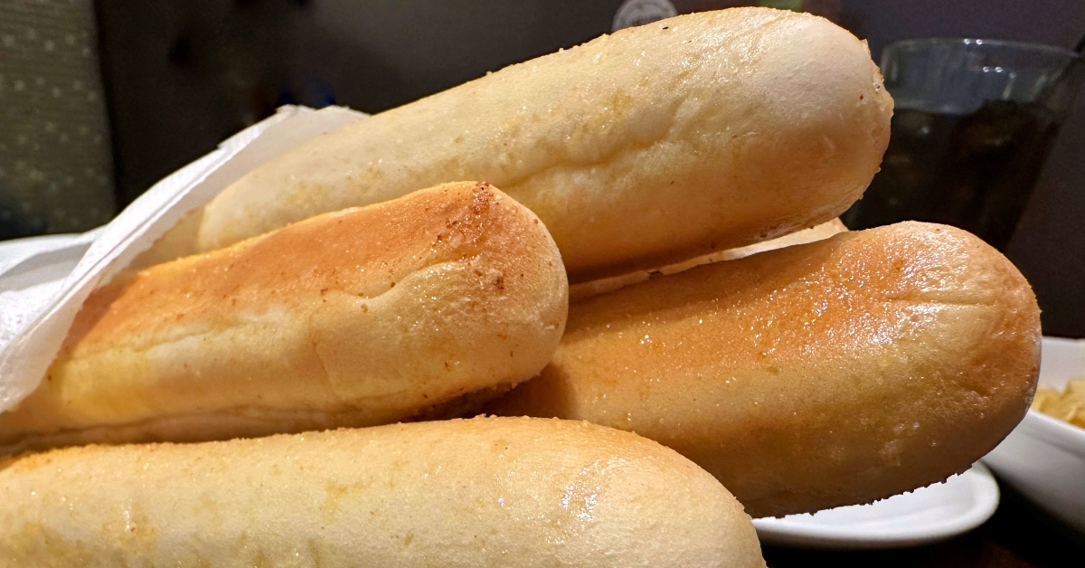 Four breadsticks wrapped in a white paper towel
