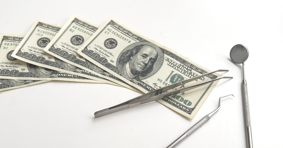 Dental mirror for oral cavity lying on dollar bills