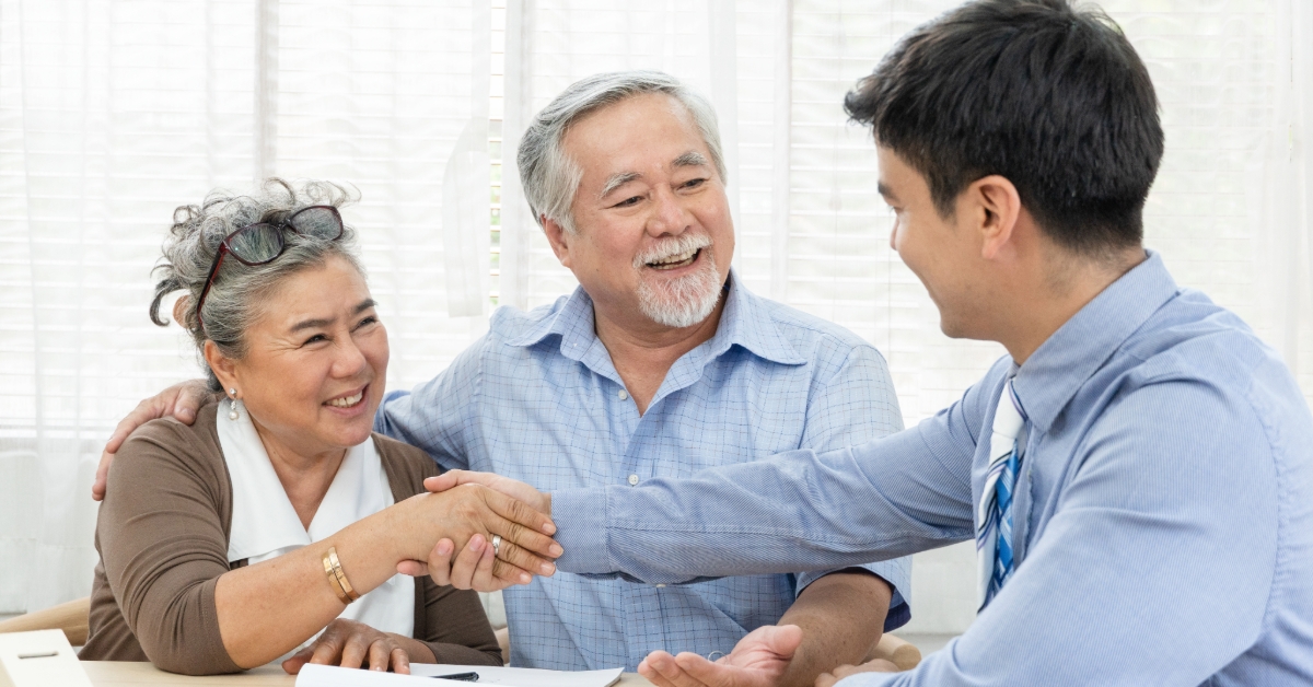 Happy smiling old couple making purchase and shaking hands with real estate agent