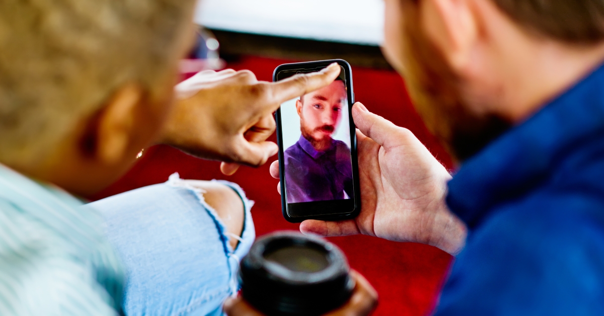 man and woman viewing photos on modern smartphone